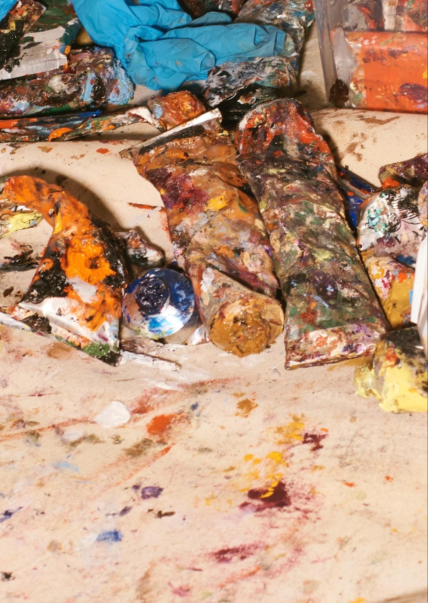 Close-up macro detail of heavy used oil paint tubes and mixed raw pigments inside a working artist atelier.